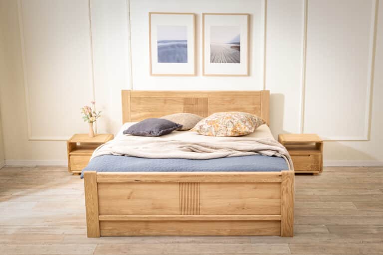 Dubová posteľ Luise z masívu prináša do spálne nadčasovú eleganciu a poctivé remeselné spracovanie. Jemné drážkovanie, oblé hrany a prirodzená kresba dubu vytvárajú harmonický celok, ktorý zahreje na pohľad aj na dotyk. Praktický úložný priestor pod zdvíhacím roštom aj v prednej časti postele ponúka inteligentné riešenie pre každodenný komfort.