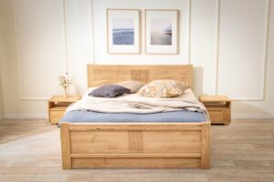 Dubová posteľ Luise z masívu prináša do spálne nadčasovú eleganciu a poctivé remeselné spracovanie. Jemné drážkovanie, oblé hrany a prirodzená kresba dubu vytvárajú harmonický celok, ktorý zahreje na pohľad aj na dotyk. Praktický úložný priestor pod zdvíhacím roštom aj v prednej časti postele ponúka inteligentné riešenie pre každodenný komfort.